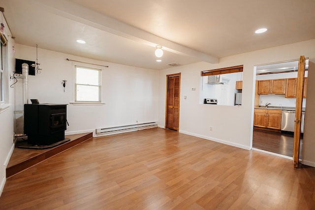 unfurnished living room with baseboard heating, a wood stove, wood finished floors, and recessed lighting