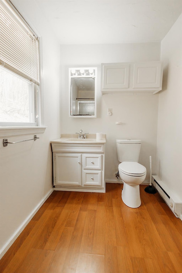 bathroom featuring vanity, toilet, baseboards, baseboard heating, and wood finished floors
