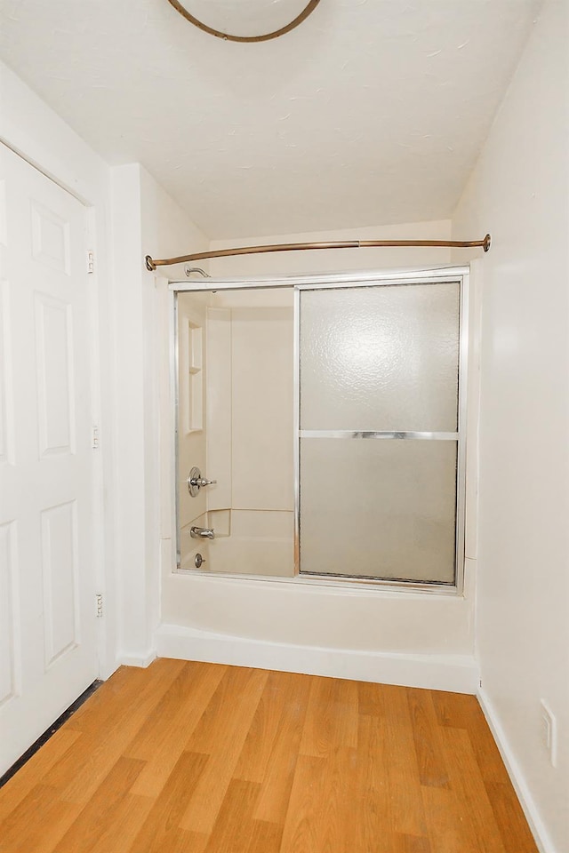 full bathroom with washtub / shower combination, wood finished floors, and baseboards