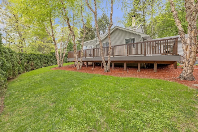 back of property with a wooden deck, a yard, and a chimney