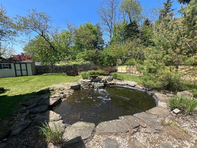 19 Millbrook Dr, Stony Brook, NY 11790 - view of yard featuring a small pond, fence, an outbuilding, and a storage shed