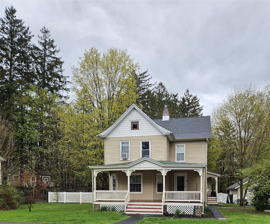 view of front facade featuring covered porch, a chimney, and a front lawn