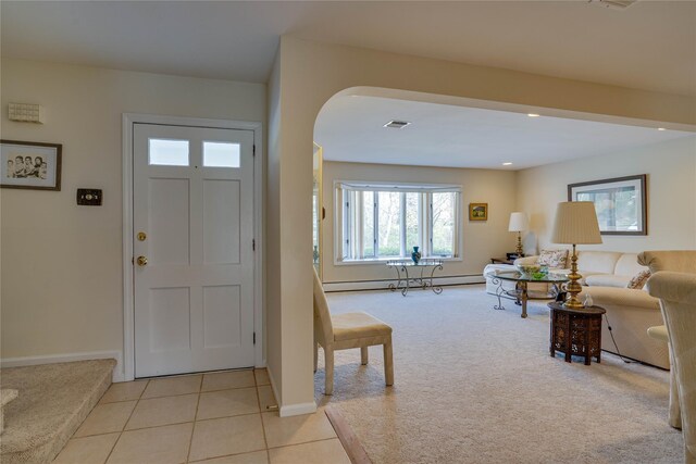 foyer entrance featuring visible vents, arched walkways, baseboards, a baseboard heating unit, and light carpet