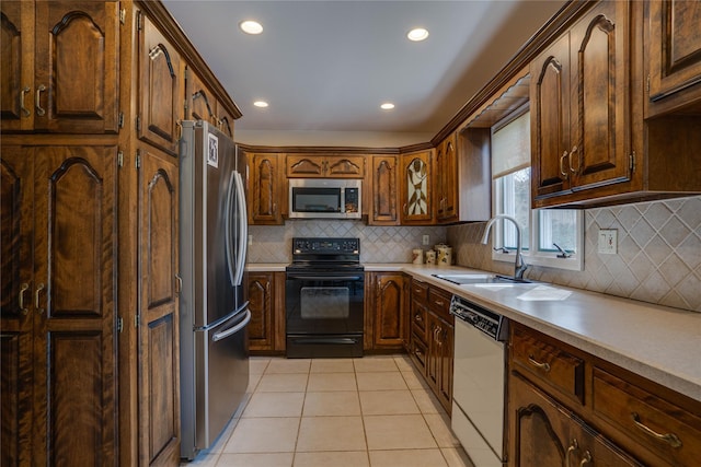 kitchen featuring backsplash, appliances with stainless steel finishes, a sink, light tile patterned floors, and recessed lighting