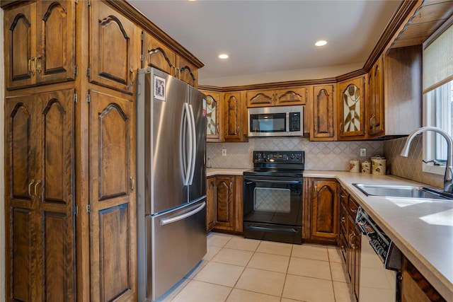kitchen with backsplash, appliances with stainless steel finishes, a sink, light countertops, and light tile patterned flooring