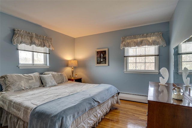 bedroom with wood finished floors and a baseboard radiator