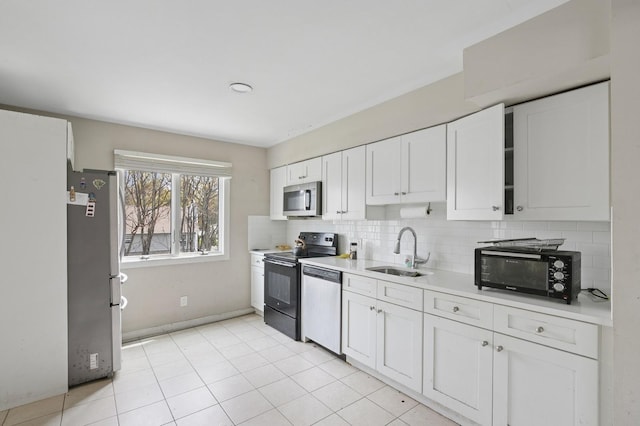 kitchen with tasteful backsplash, stainless steel appliances, light countertops, a sink, and white cabinetry