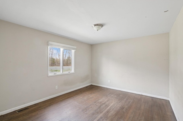 empty room featuring visible vents, wood finished floors, and baseboards