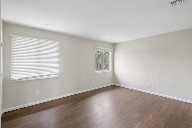 unfurnished room with baseboards, visible vents, and wood finished floors