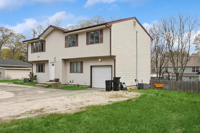 view of front of property featuring fence, central AC unit, an attached garage, and a front lawn