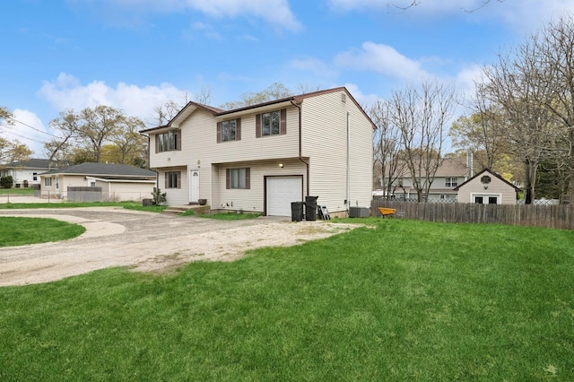 rear view of house with fence, central air condition unit, a garage, driveway, and a lawn