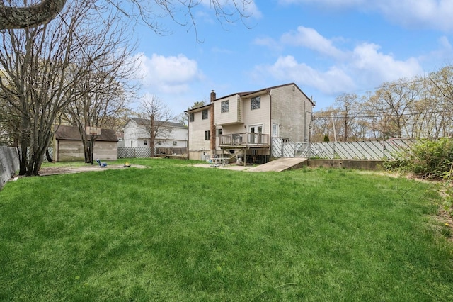 back of property with a chimney, a wooden deck, a fenced backyard, and a yard