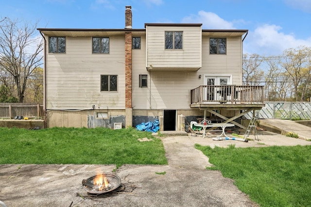 back of house with a fire pit, fence, a wooden deck, and a yard