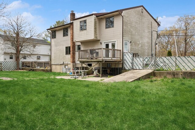 back of house with a chimney, a yard, a wooden deck, and a fenced backyard