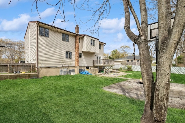 rear view of property featuring a chimney, fence, and a yard