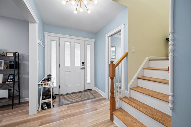 foyer with stairs, baseboards, an inviting chandelier, and light wood-style flooring