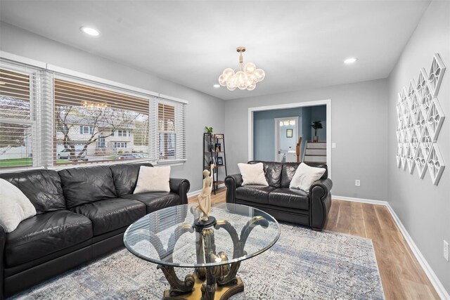living room featuring an inviting chandelier, baseboards, wood finished floors, and a healthy amount of sunlight