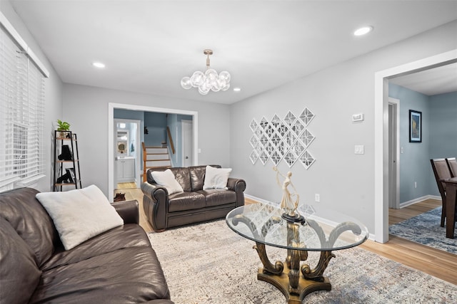 living area featuring a notable chandelier, stairs, recessed lighting, baseboards, and wood finished floors