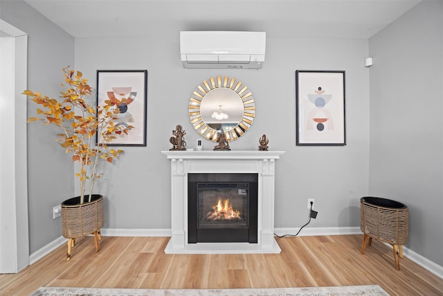 room details featuring a glass covered fireplace, baseboards, a wall mounted AC, and wood finished floors