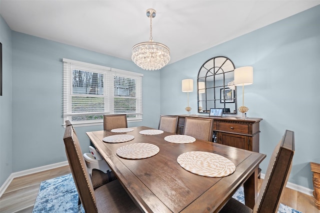 dining room featuring baseboards, light wood finished floors, and a chandelier