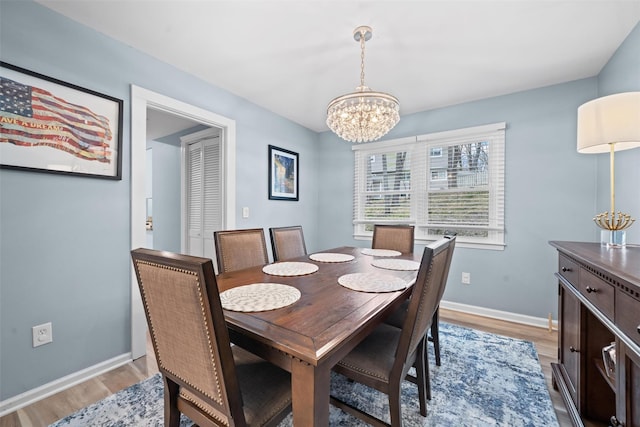 dining room featuring baseboards, an inviting chandelier, and light wood-style floors