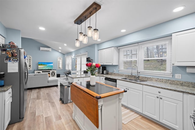 kitchen with vaulted ceiling, a sink, white cabinets, open floor plan, and stainless steel appliances
