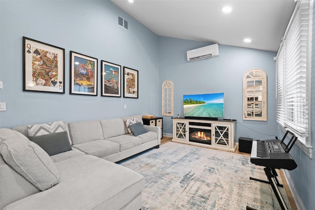 living room with a glass covered fireplace, recessed lighting, baseboards, a wall unit AC, and vaulted ceiling
