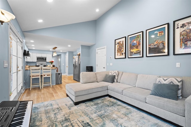 living room with recessed lighting, high vaulted ceiling, and light wood-style floors