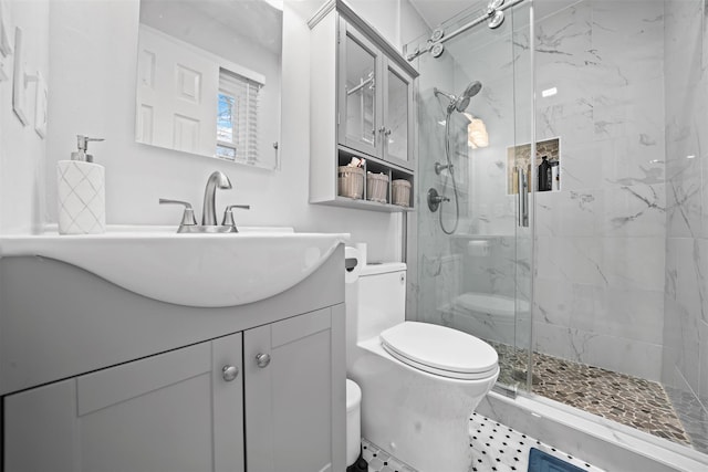 bathroom featuring toilet, a marble finish shower, and vanity