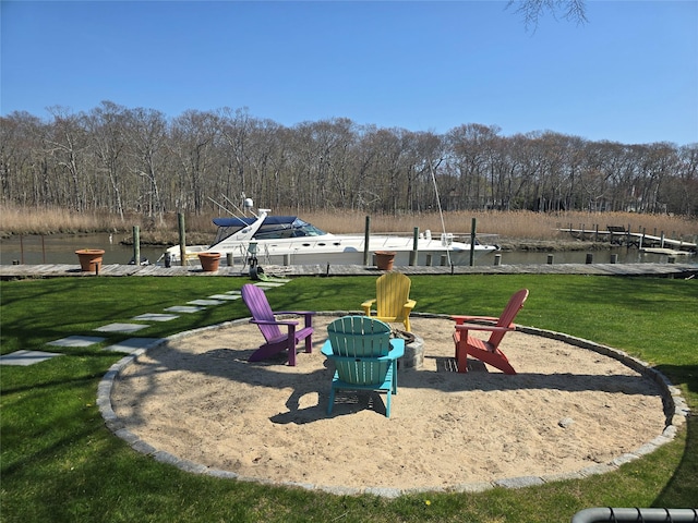 view of property's community featuring a water view, a forest view, a boat dock, a lawn, and a fire pit