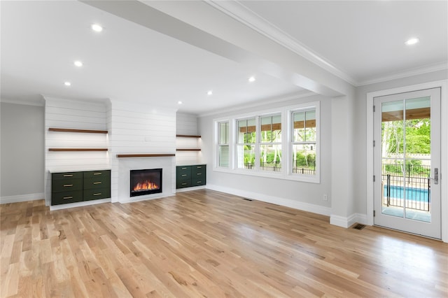33 Lagoon Ct, Jamesport, NY 11901 - unfurnished living room featuring crown molding, healthy amount of natural light, baseboards, light wood finished floors, and a glass covered fireplace
