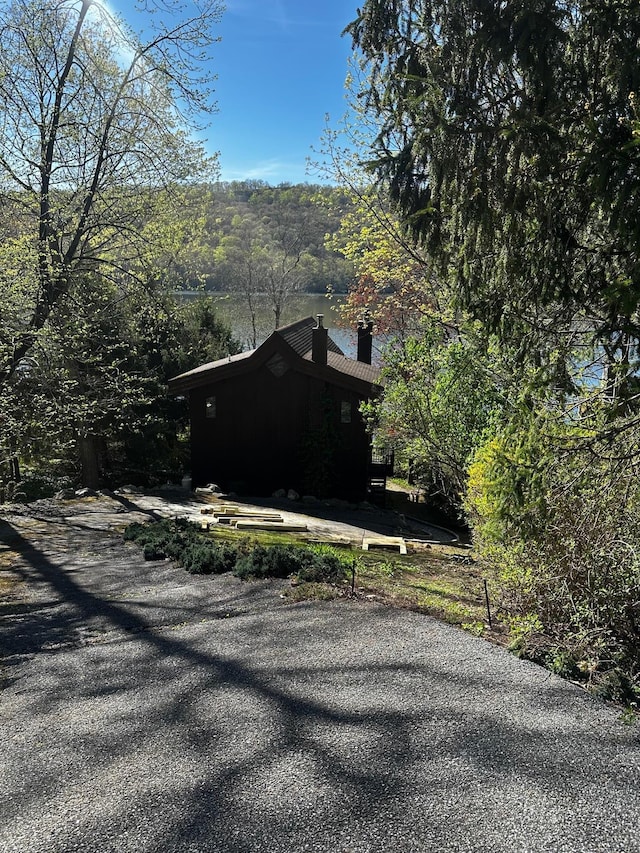view of side of home featuring a view of trees and a chimney