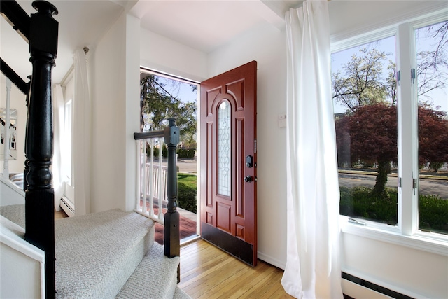 entrance foyer featuring a baseboard heating unit, plenty of natural light, light wood-style floors, and a baseboard radiator