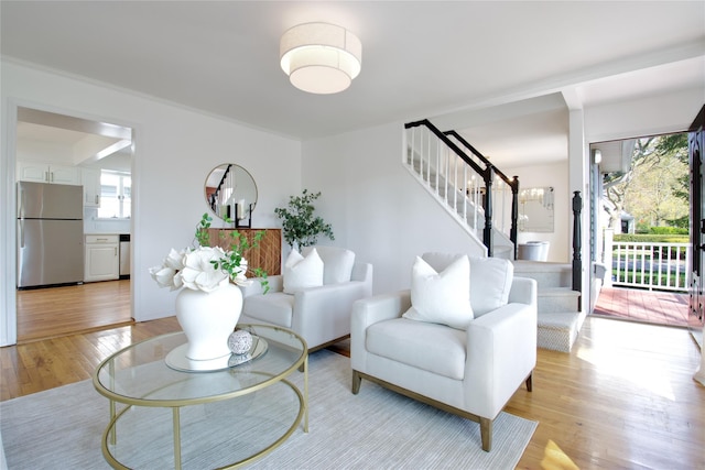 living area featuring stairs and light wood-style floors