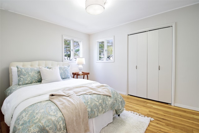 bedroom featuring baseboards, light wood-style flooring, and a closet