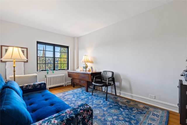 home office with baseboards, radiator, and wood finished floors