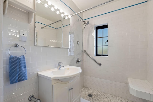 bathroom featuring tile walls, a tile shower, and vanity