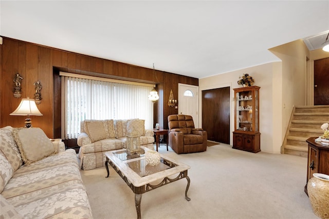 living room featuring wood walls, light colored carpet, and stairway