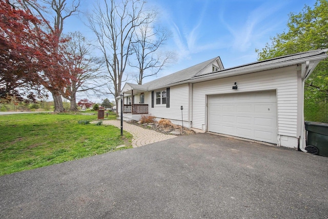 single story home featuring an attached garage, aphalt driveway, and a front yard