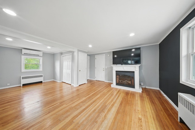 unfurnished living room featuring crown molding, a wall mounted AC, radiator, and light wood-style floors