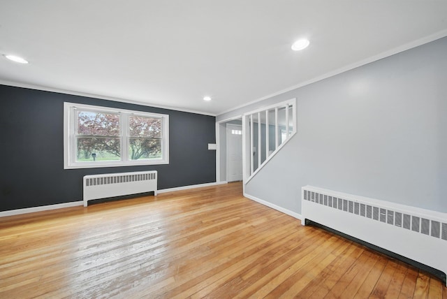unfurnished living room featuring hardwood / wood-style flooring, ornamental molding, baseboards, and radiator