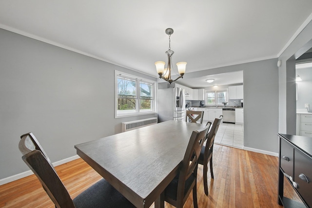 dining space featuring radiator, a wealth of natural light, light wood finished floors, and a chandelier