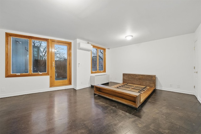 bedroom featuring baseboards, wood finished floors, and a wall mounted air conditioner