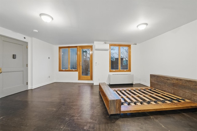 unfurnished bedroom featuring baseboards, a wall unit AC, and radiator heating unit