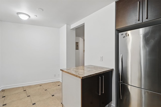 kitchen featuring baseboards, freestanding refrigerator, and light tile patterned floors