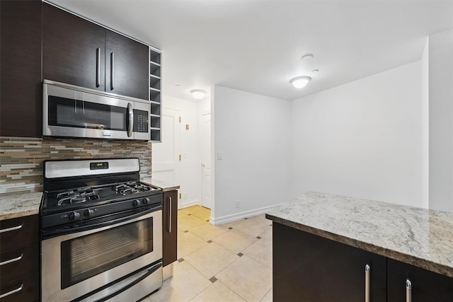 kitchen featuring backsplash, appliances with stainless steel finishes, open shelves, baseboards, and light stone counters