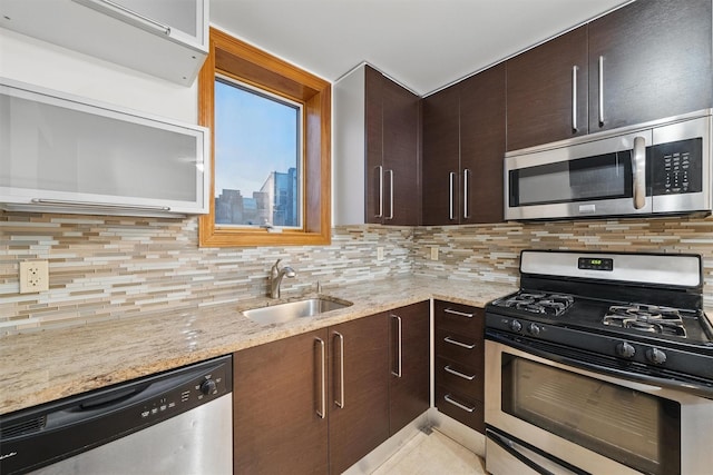 kitchen with a sink, appliances with stainless steel finishes, decorative backsplash, and light stone countertops