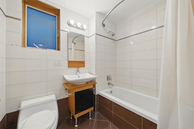 bathroom with tile walls, tile patterned flooring, vanity, tiled shower / bath, and toilet