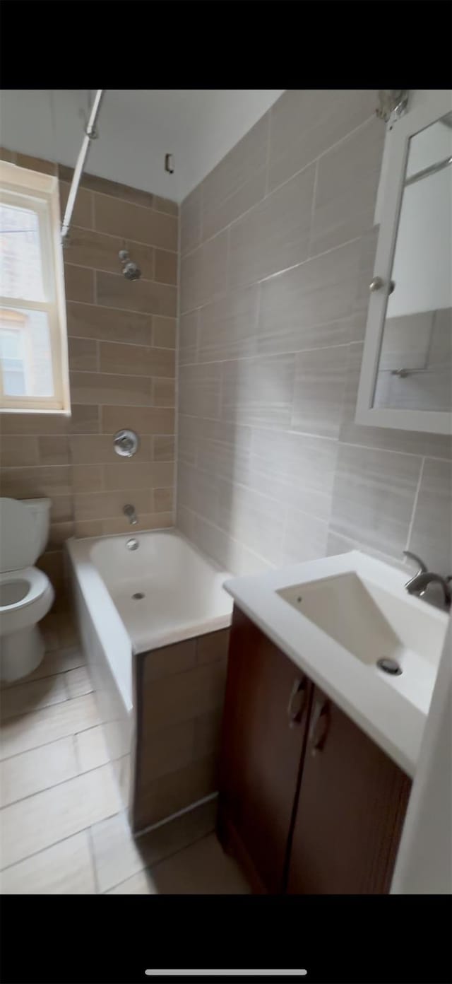 563 Williams Ave, Brooklyn, NY 11207 - full bath with tile walls, toilet, shower / bath combination, vanity, and tile patterned flooring