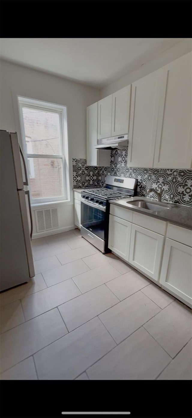 563 Williams Ave, Brooklyn, NY 11207 - kitchen featuring decorative backsplash, a sink, freestanding refrigerator, under cabinet range hood, and stainless steel gas range oven